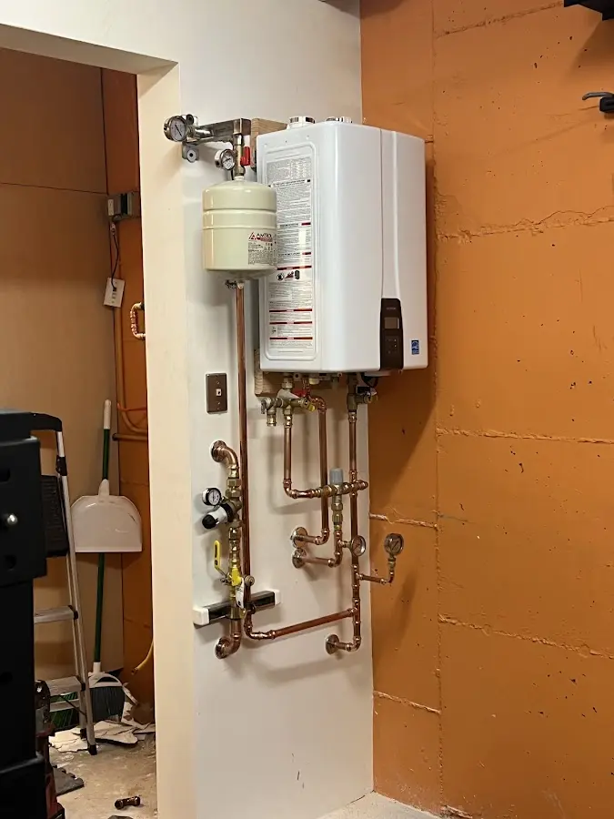 Plumbing technician inspecting water heater connections in Rumford